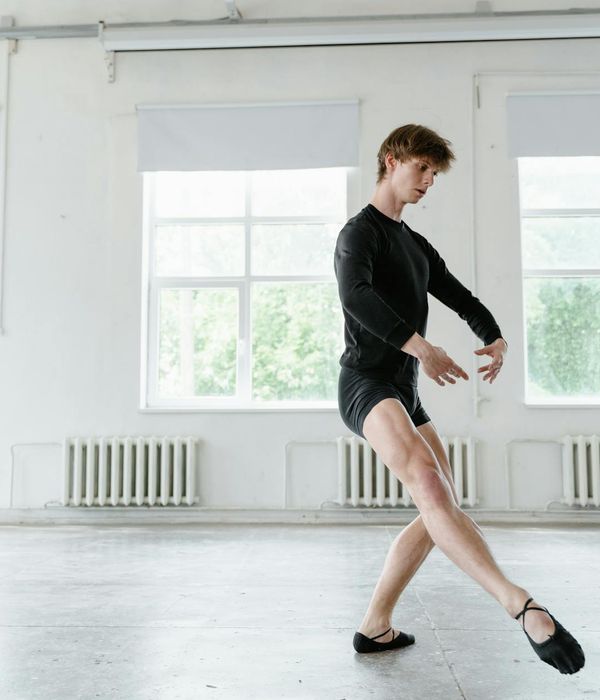 Man in a controlled movement pose in a minimalist dark studio.